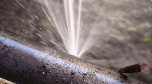 A cracked pipe spraying under pressure before repair